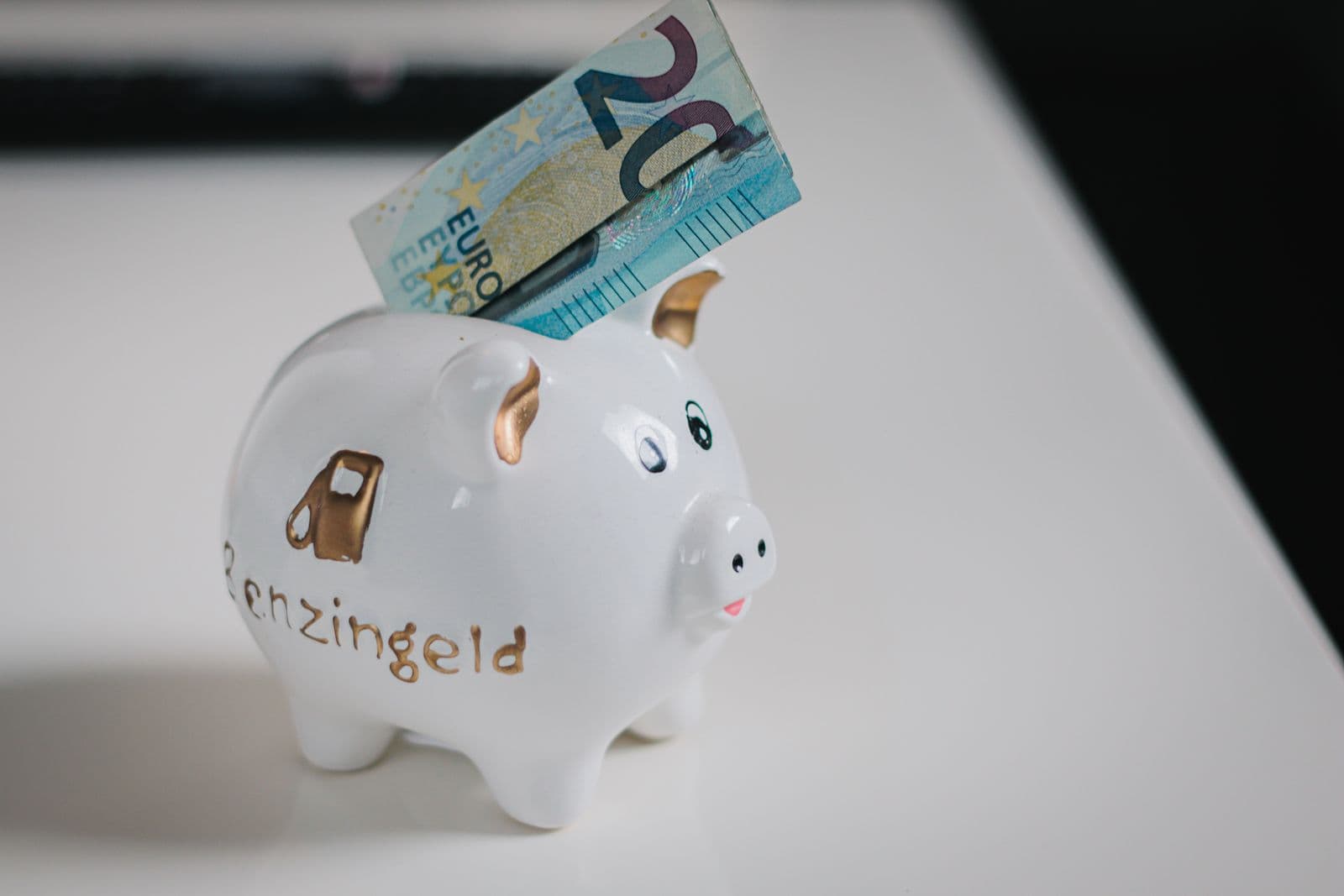 Tirelire blanche dans laquelle est glissé un billet de 20 euros